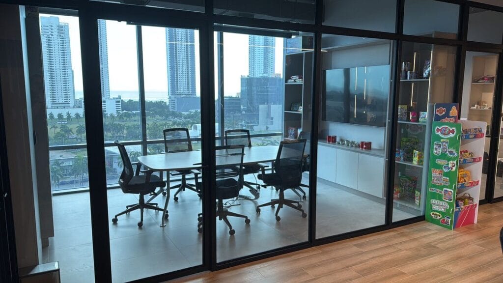 Espacio de reuniones en las oficinas de Candies Supplier con una mesa redonda y vistas al exterior.
